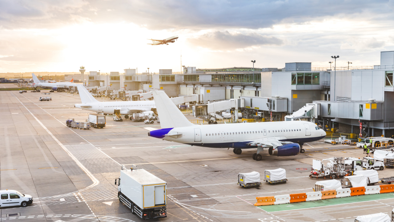 Auf dem Flughafen am Gate geparkte Flugzeuge und ein Flugzeug, das im Hintergrund startet.