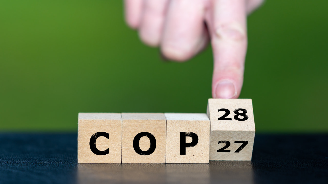Holzwürfel mit den Buchstaben C O P und der Zahl 28 vor einem schlichten Hintergrund für die grüne Energiewende