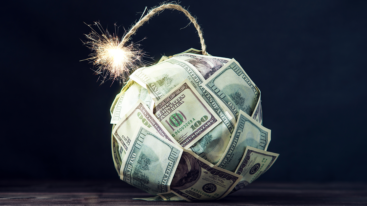 Große Bombe von Geld Hundertdollarscheinen mit einem brennenden Schein. Kaum Zeit vor der Explosion. Das Konzept der Finanzkrise