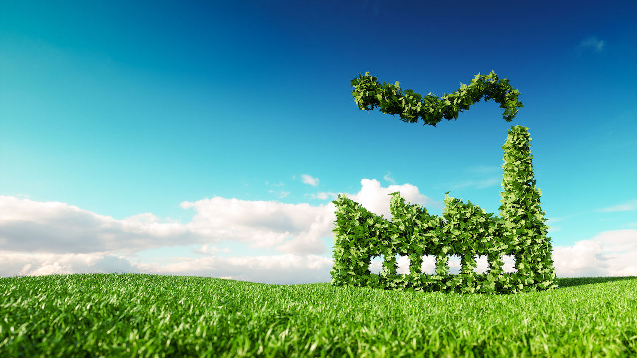 Eco friendly industry concept. 3d rendering of green factory icon on fresh spring meadow with blue sky in background.