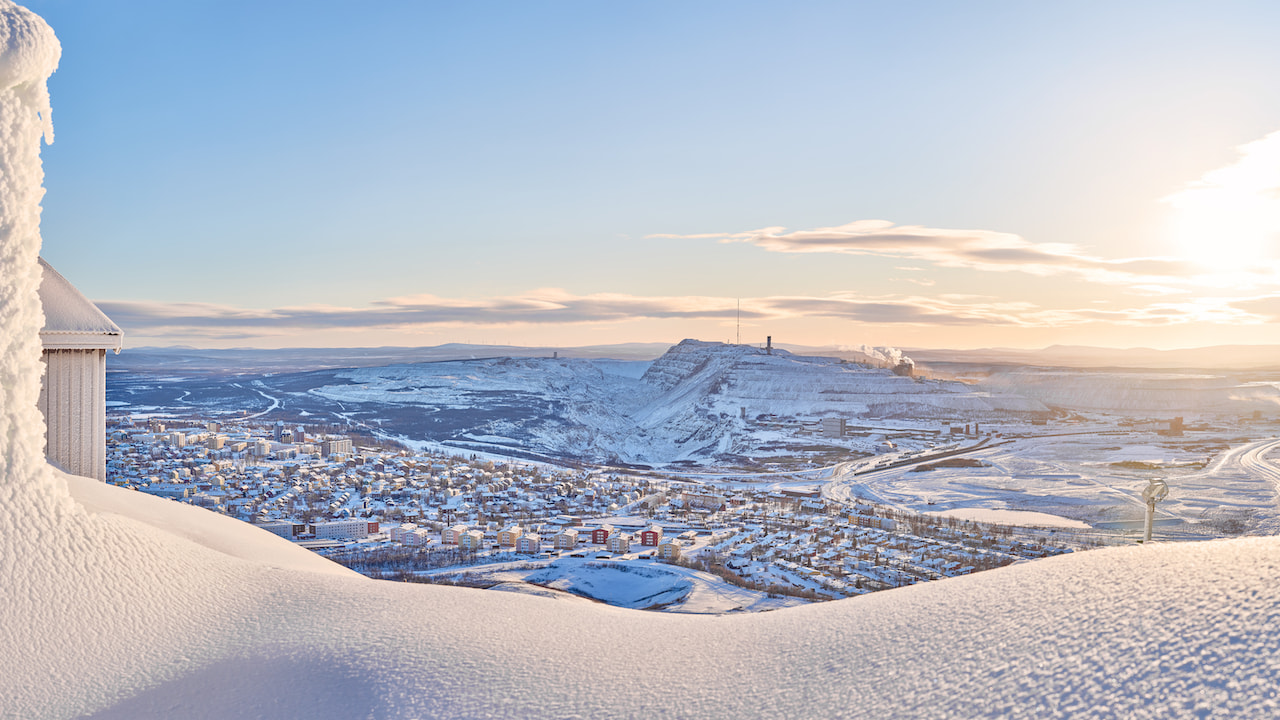 Eisenerz-Mine in Kiruna City. View of Kiruna city and the iron ore mine on the mountain Kiirunavaara seen from the snowy mountain peak Luossavaara.