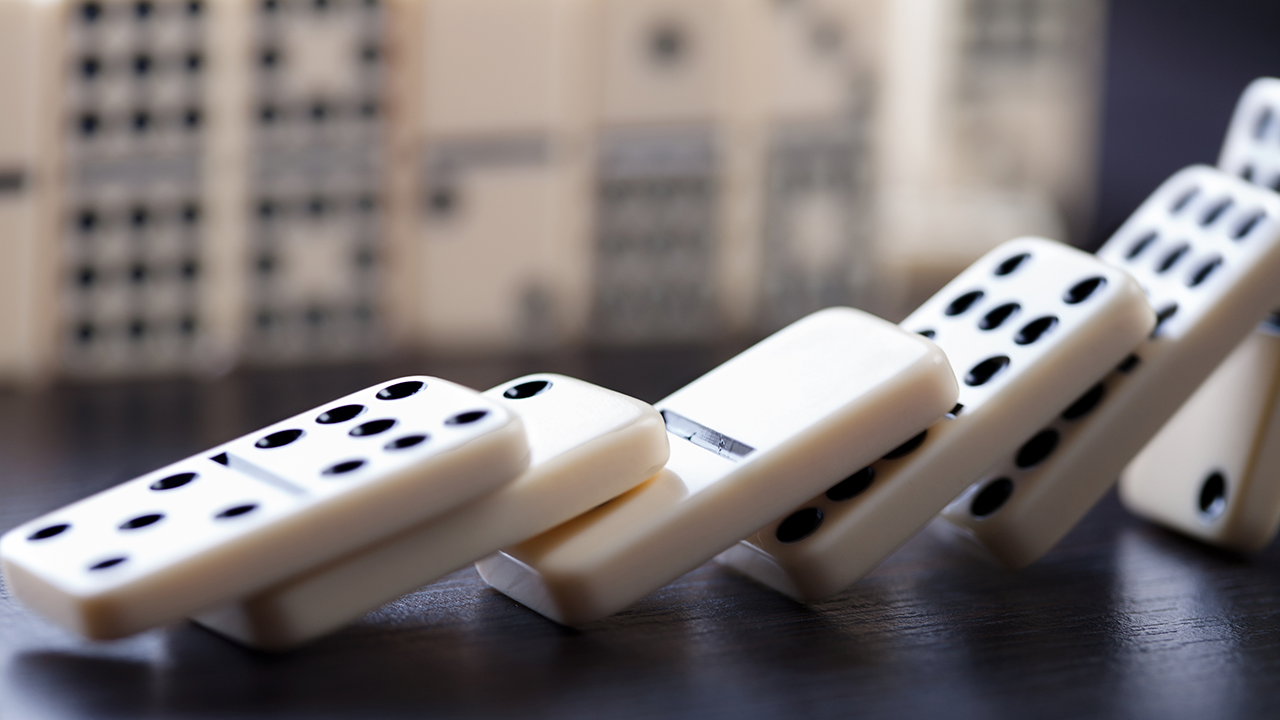 Domino-Steine und Kettenreaktion auf schwarzem Hintergrund