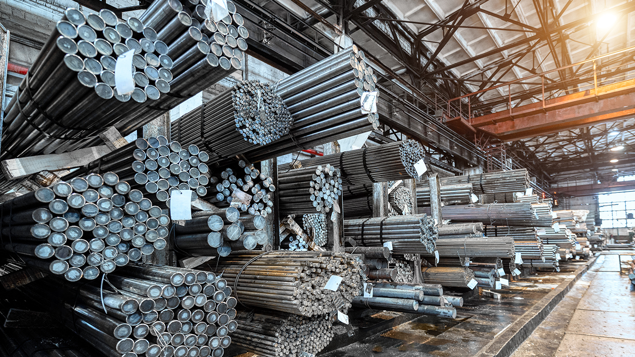 Blick in eine Lagerhalle für Metalle in Rollen. Viele Packungen mit Metallstangen liegen auf den Regalen.