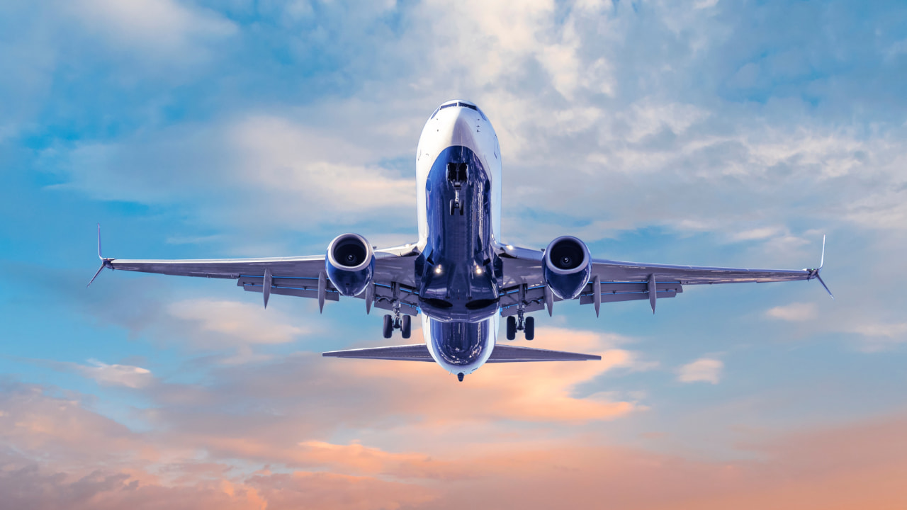 Passagierflugzeug am Himmel mit rosafarbenen Wolken