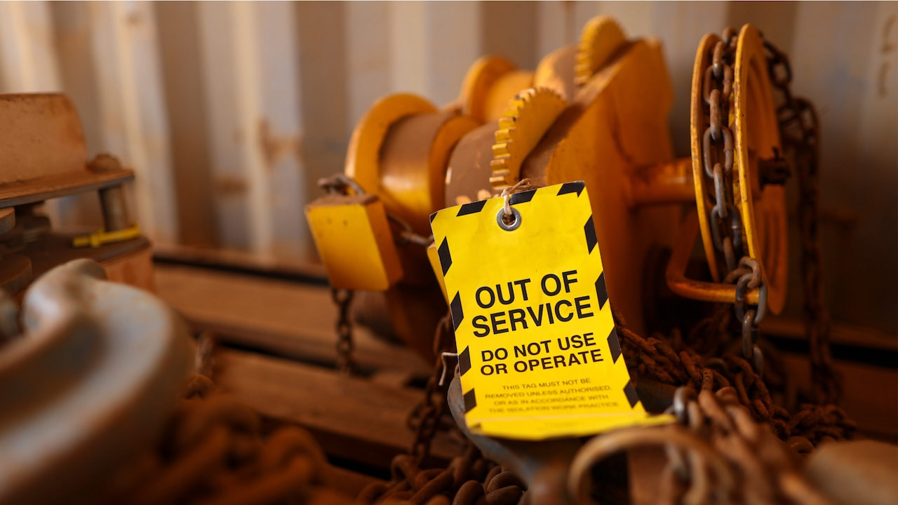 Industriewinde mit Ketten und Warnschild „OUT OF SERVICE – DO NOT USE OR OPERATE“