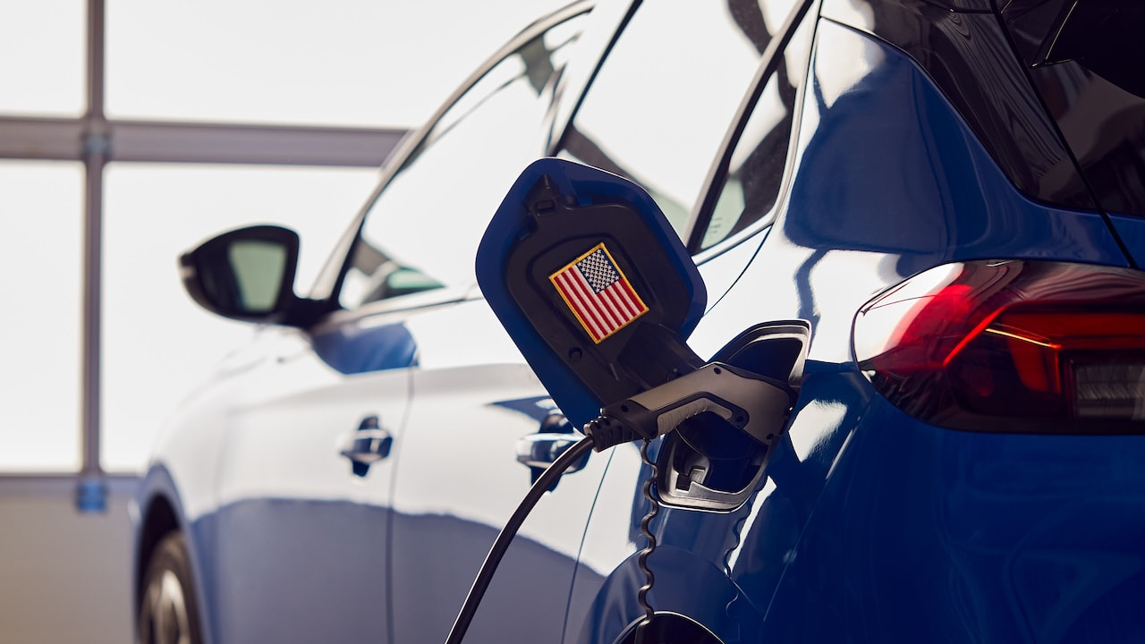 Charging Cable Attached To Zero Emission Electric Car With US Flag Sticker In Garage