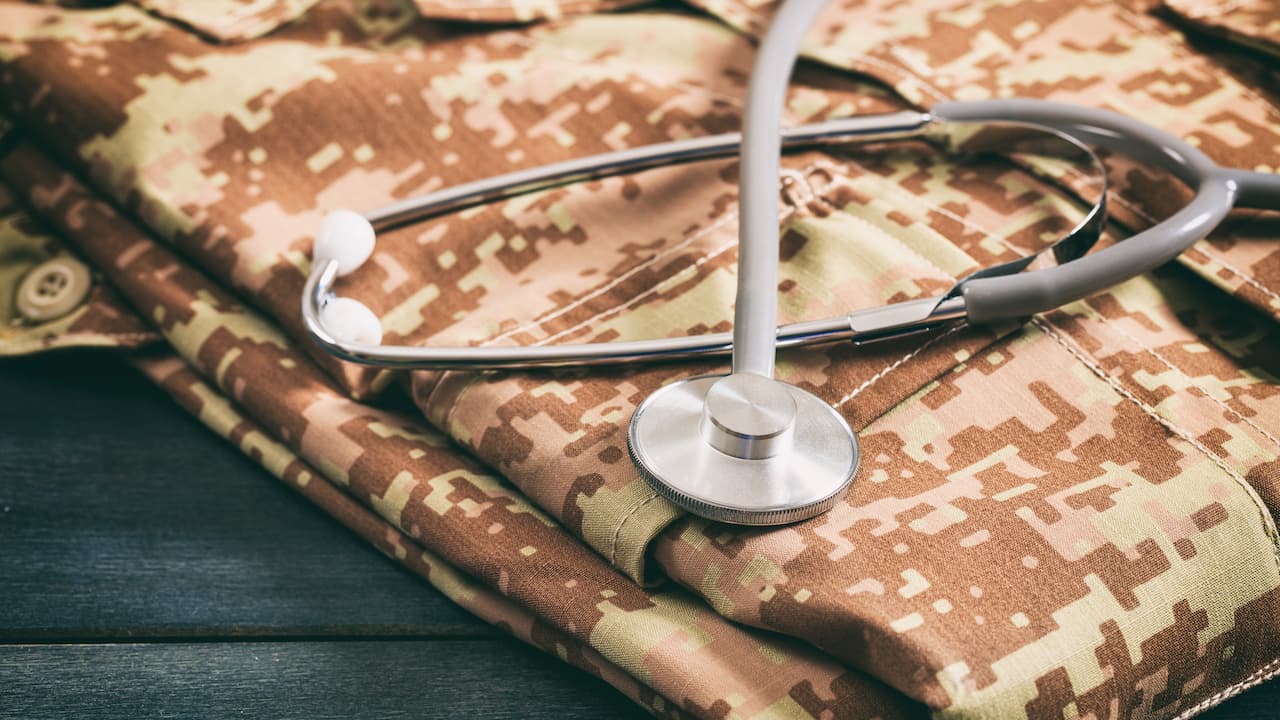 Military medical concept with stethoscope and American military digital pattern uniform, folden on wooden background