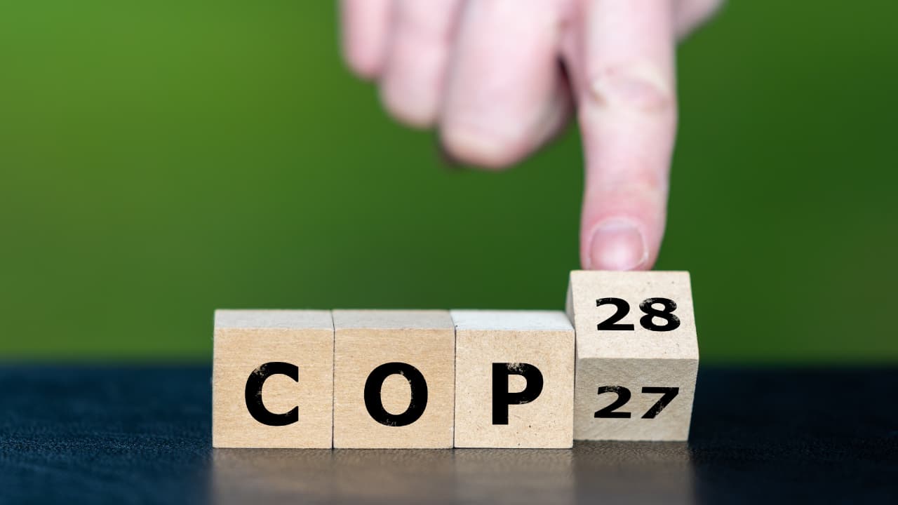 Symbol for the next climate conference. Hand turns cubes and changes the expression 'COP27' to 'COP28'.