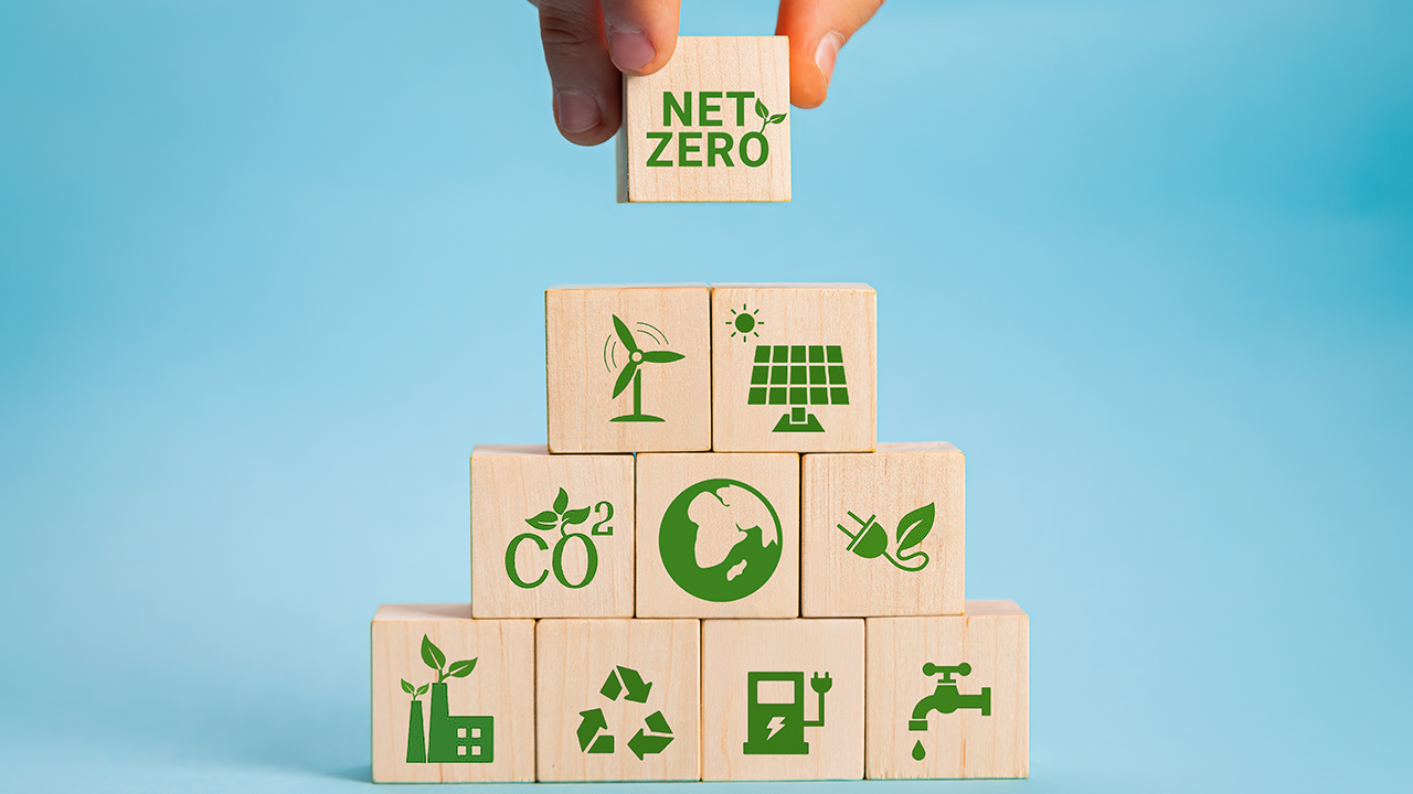 Netto-Null- und CO2-neutrales Konzept. Netto-Null-Ziel für Treibhausgasemissionen. Klimaneutrale langfristige Strategie. Hand legen Sie hölzerne Würfel mit grünem Nettopreis und grüner Symbol auf grauem Hintergrund.