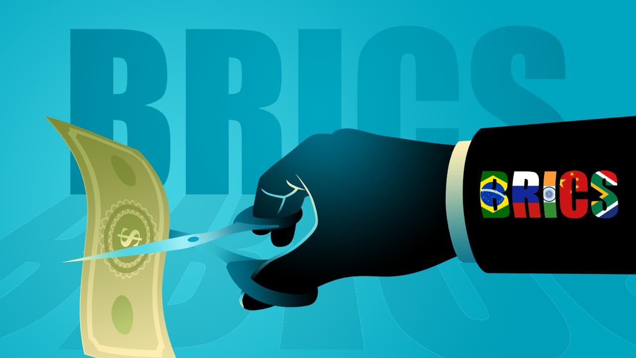 Hand mit Schere und "BRICS" in Farbbuchstaben am Arm schneidet Dollarnote durch.