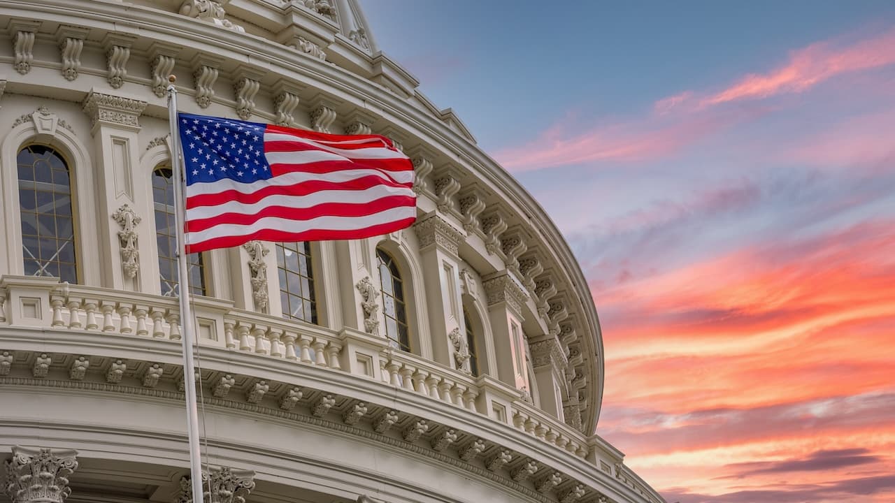 Aussicht auf den Capitol Rotunda Dome der Vereinigten Staaten in Washington DC mit der Star Spangled American Flag auf buntem, dramatischem Hintergrund beim Sonnenuntergang