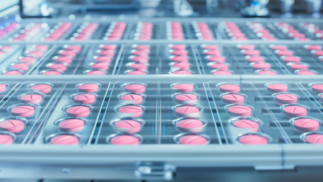 Makroaufnahme rosafarbener Pillen während des Produktions- und Verpackungsprozesses auf der modernen pharmazeutischen Fabrik. Herstellung von Medizinprodukten.